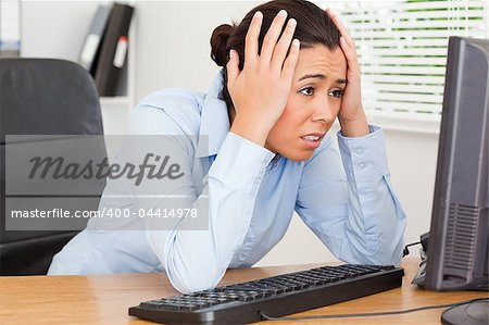 Good looking upset woman looking at a computer screen while sitting at the office