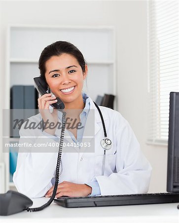 Good looking woman doctor on the phone while sitting in her office