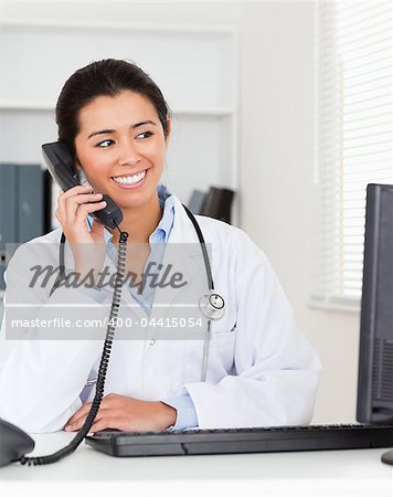 Beautiful woman doctor on the phone while sitting in her office