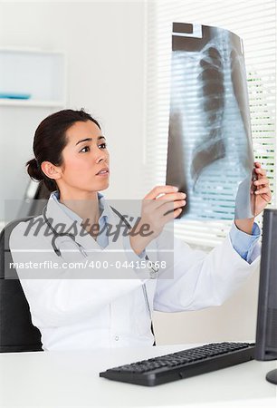 Pretty female doctor looking at a x-ray in her office