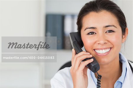 Gorgeous female doctor on the phone and posing in her office