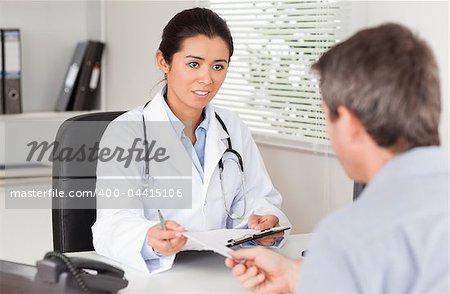 Patient giving his beautiful female doctor a piece of paper in her office