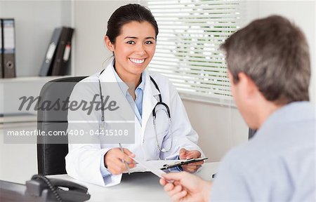 Patient giving his attractive female doctor a piece of paper in her office