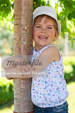 Little adorable girl posing by tree in the park