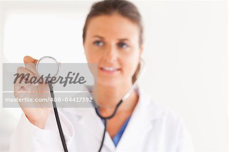 gorgeous brunette doctor showing stethoscope to the camera in the surgery