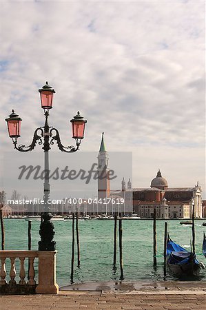Vertical oriented photo of venetian lamppost, gondola on Grand Canal and San Giorgio Maggiore church in Venice, Italy.