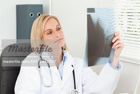 Charming doctor holding x-ray in her office