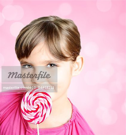 Beautiful little girl with lolipop in front of the pink background