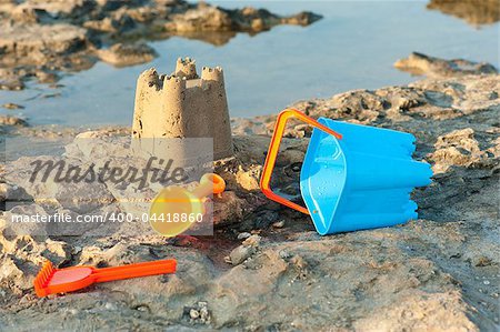 A sand castle and toy tools in scenic setting