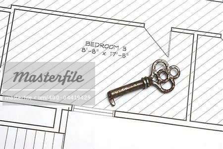 An old skeleton key rests on the architectual drawings of blueprints for a new house construction.