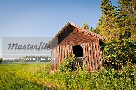 A red barn on a field next to the woods