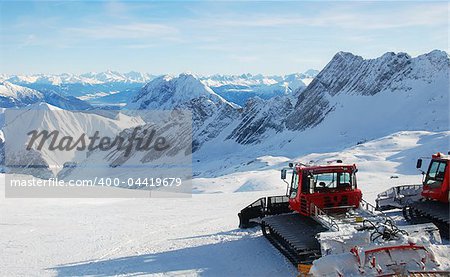 Piste preperation vehicles with view over the alps