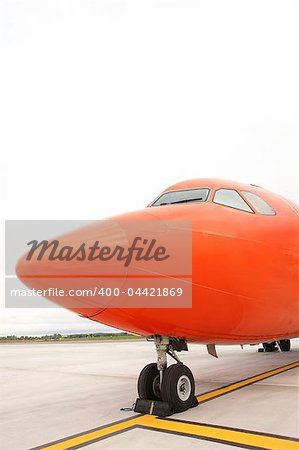 A picture of an orange business jet standing on the apron space for your text