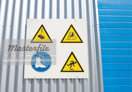 industrial warning signs on a warehouse with a blue roller door