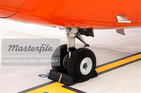 A picture of an orange undercarriage of a business jet standing on the apron