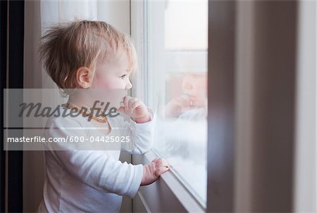 Portrait de bébé fille regardant dehors la fenêtre