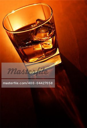 Glass of whiskey and ice on brown bar counter