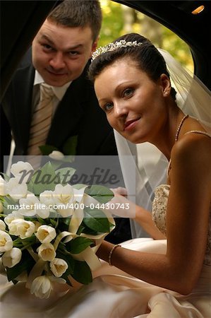 The groom helps the bride to leave from the automobile