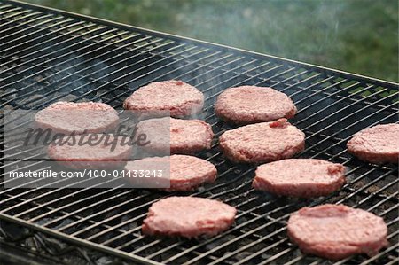 Raw burgers on the grill waiting to be cooked