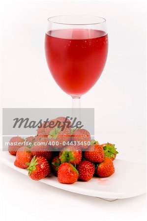 Fresh Strawberrys and glass of juice set against a plain background