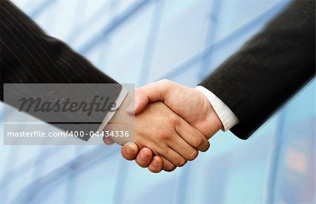 business hand shake and a office in background, slightly motion blur in the Suits, focus at the hands