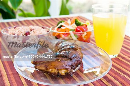 Barbecued chicken leg also known as Jerk Chicken - Caribbean style served with vegetables, rice and lemonade.  Shallow DOF.