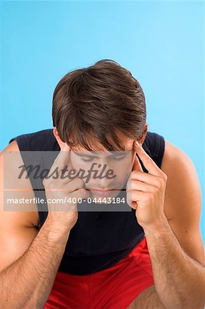 portrait of a young man having a headache over blue background