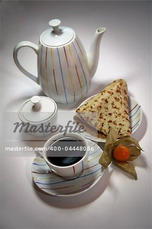 Teapot, cup from coffee and a pancake on a plate, decorated with a yellow berry