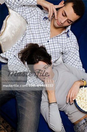 young couple watching tv at home and smiling