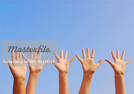 Raised hands on blue sky background with copy space