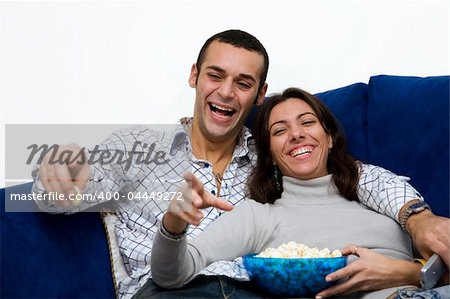 young couple watching tv at home and laughing