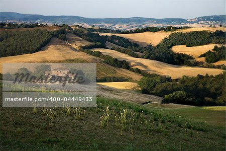 Rolling hills and building in countryside in Tuscany, Italy.