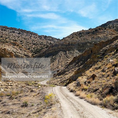 Dirt road winding through rocky desert cliffs of Cottonwood Canyon, Utah.