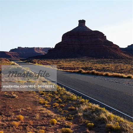 Two lane road travelling toward Garden of the Gods rock formation in Monument Valley, Utah.