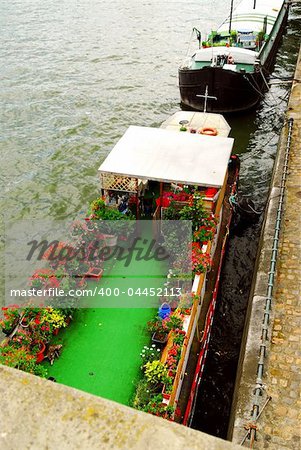 Charming houseboats with flowers docked on Seine in Paris France