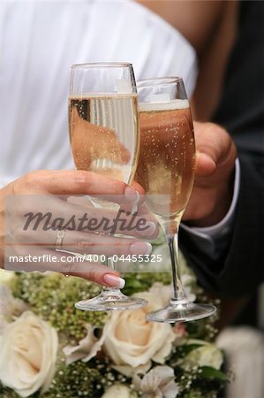 Glasses of champagne of champagne in a hand of the groom and bride