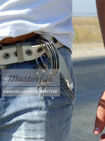 The handcuffs hanging on a belt of jeans