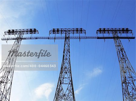Three power pylons towering under the blue sky