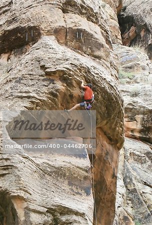 A rock climber works his way over an overhang. He is hanging onto the nose of the problem.
