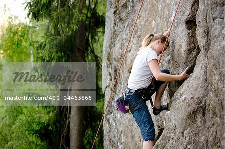 A female climber, climbing using a top rope on a steep rock face (crag)