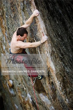 A male rock climber on a steep rock face.