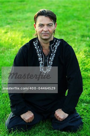 Man sitting cross legged in a zen position with eyes opened.