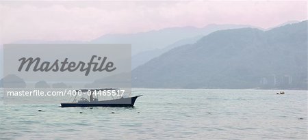 Fisherman on his boat in the bay at sunrise