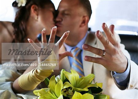 The groom and the bride kiss, showing wedding rings