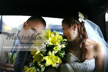 The groom and the bride with a bouquet from lilies in the automobile