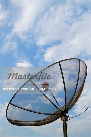 A satellite dish over a slightly cloudy sky.