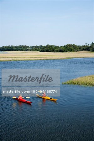Two teenage boys kayaking through marshland on Bald Head Island, North Carolina.