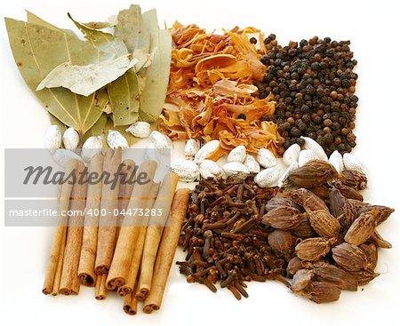 An assortment of fragrant, richly flavored spices - bay leaves, mace, peppercorns, black pepper, silver cardamom pods, cloves and cinnamon.