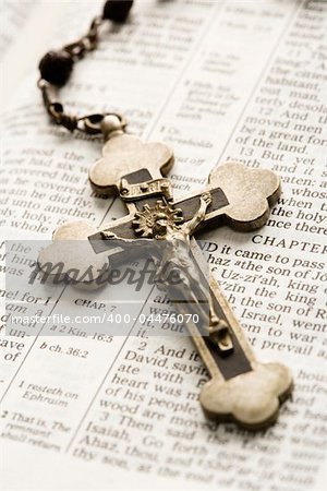 Crucifix on rosary lying on open Bible.