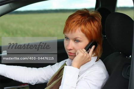 Red-haired woman with mobile-phone in a car